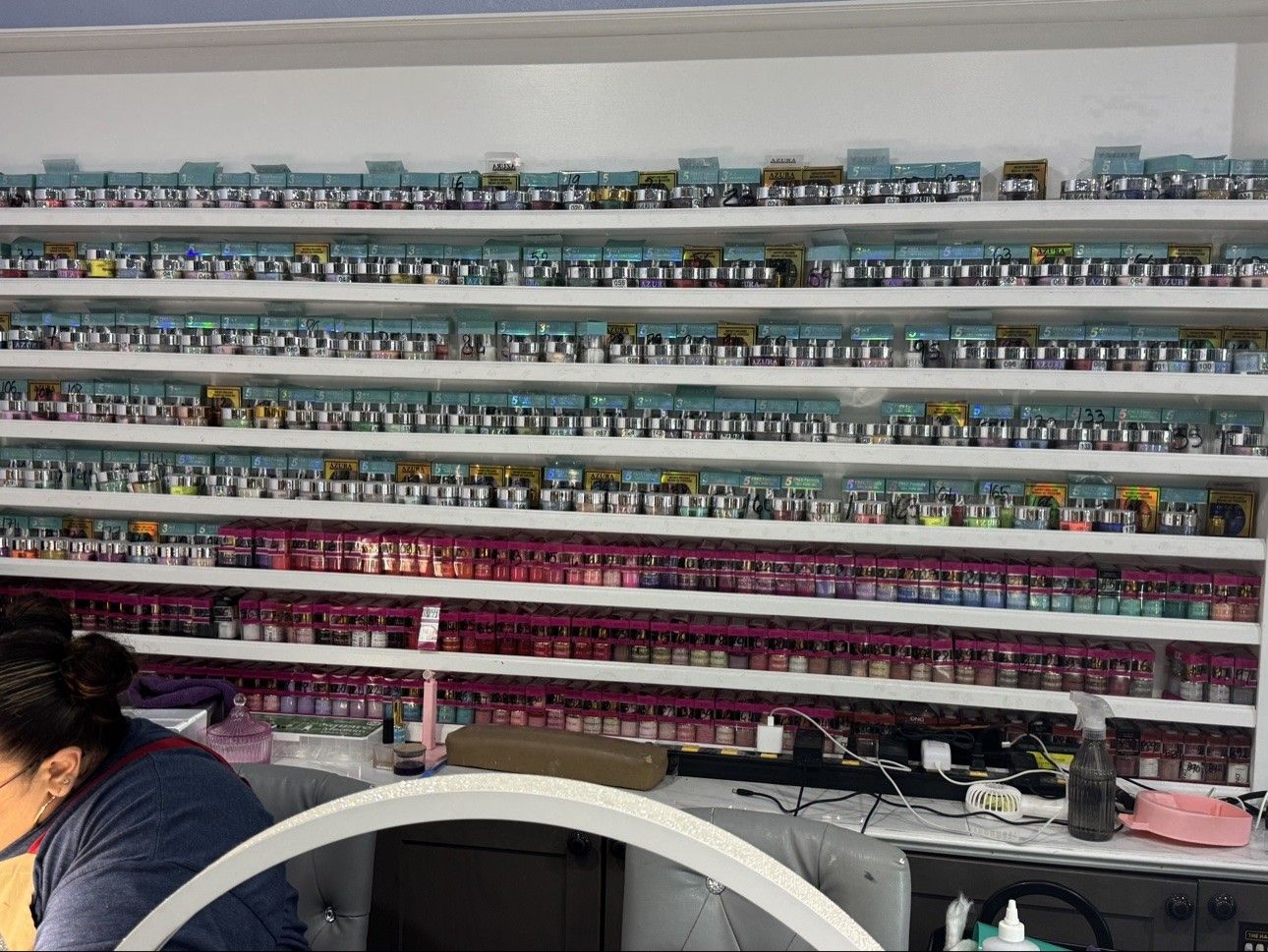 Color wall at the nail stations at Euro Nail Lounge — dip powder shelves beside a manicure station