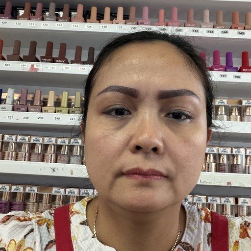 Lynn, nail technician at Euro Nail Lounge, in front of the salon's nail polish wall
